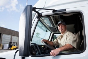 Truck driver sitting in cab of semi-truck